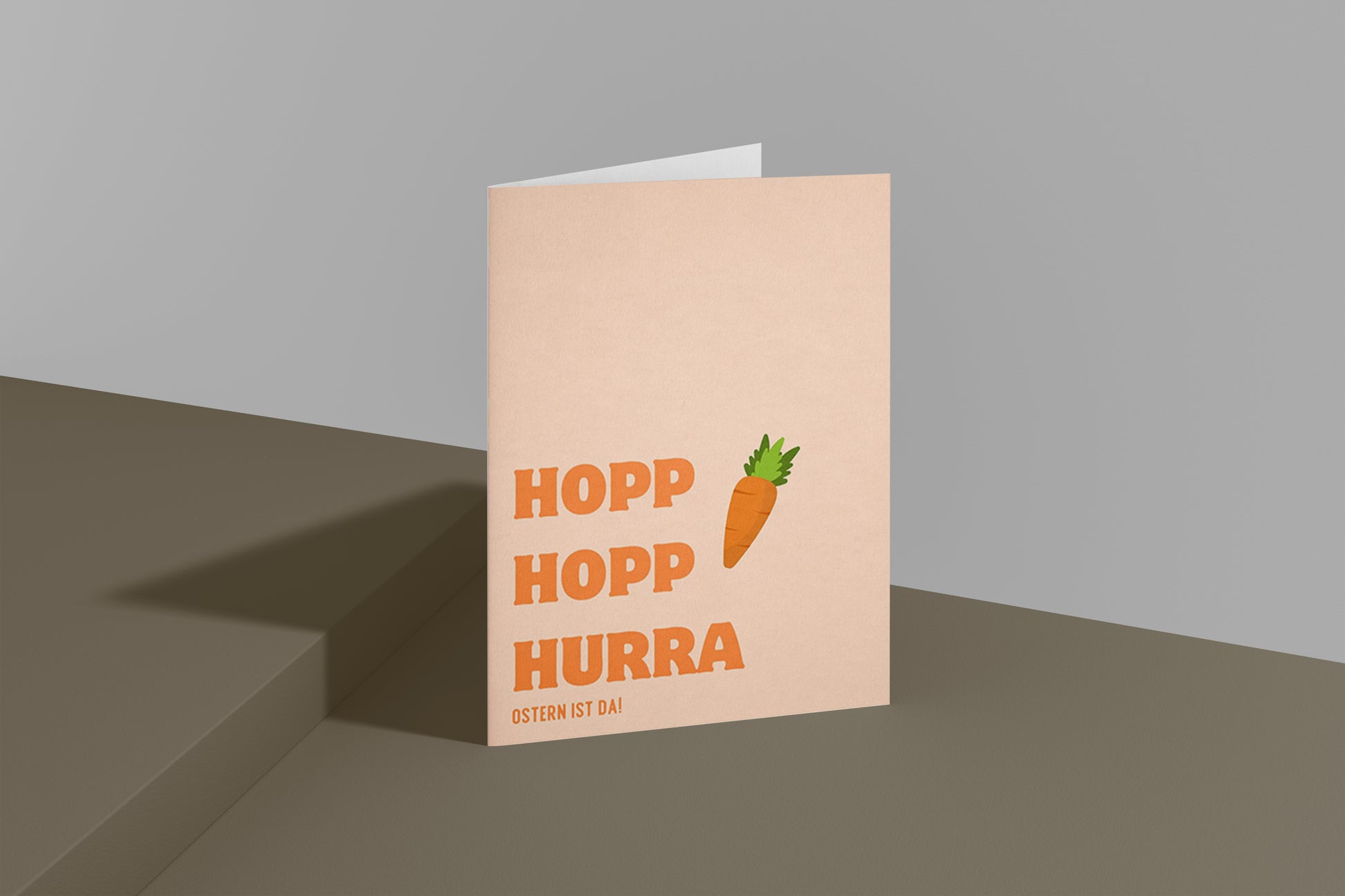 Moderne Osterkarte mit dem Schriftzug „Hopp Hopp Hurra – Ostern ist da“. Minimalistisches Design mit Karotte Illustration und warmen Pastellfarben. Perfekt als humorvolle Osterkarte für Freunde oder Familie.