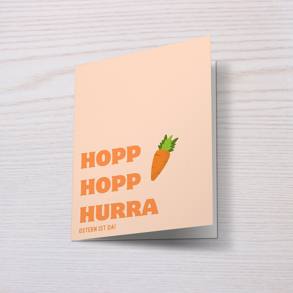 Moderne Osterkarte mit dem Schriftzug „Hopp Hopp Hurra – Ostern ist da“. Minimalistisches Design mit Karotte Illustration und warmen Pastellfarben. Perfekt als humorvolle Osterkarte für Freunde oder Familie.