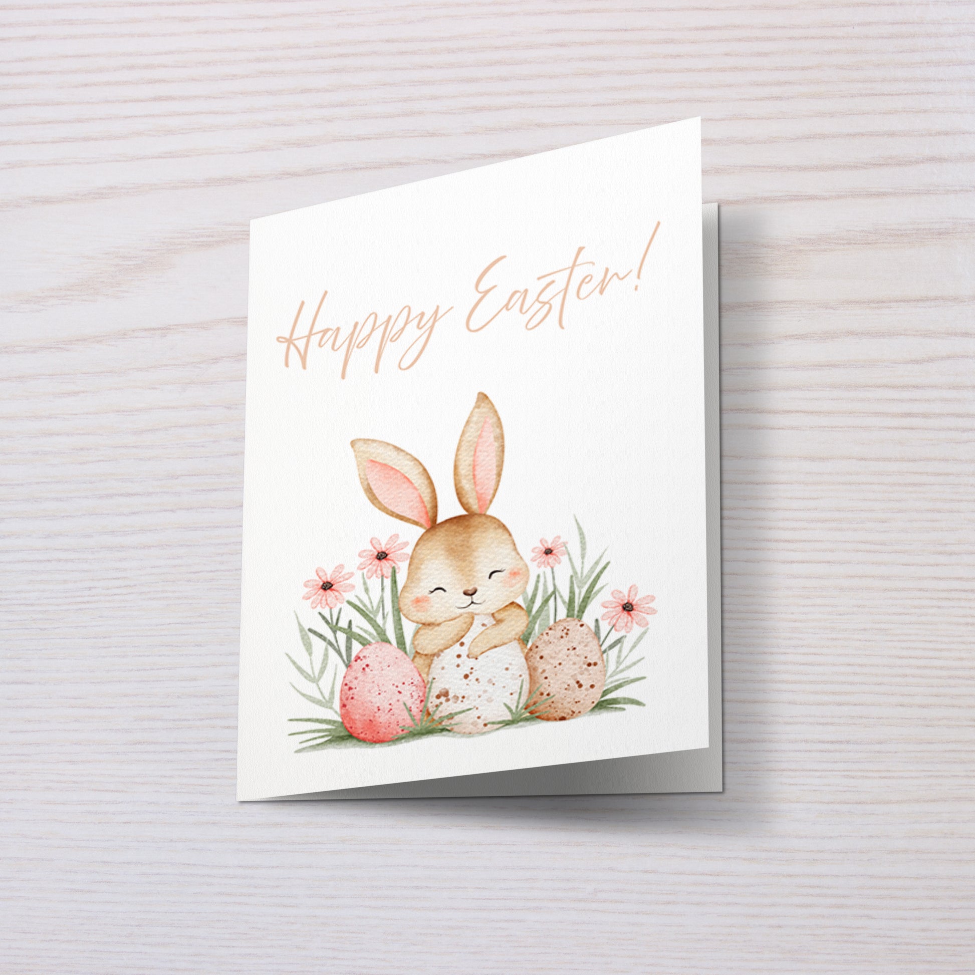 Süße Osterkarte mit einem niedlichen Hasen, der zwischen bunten Ostereiern und Frühlingsblumen sitzt. Aquarell Illustration mit sanften Pastellfarben und dem Schriftzug „Happy Easter“. Perfekt für Ostergrüße an Familie und Freunde.