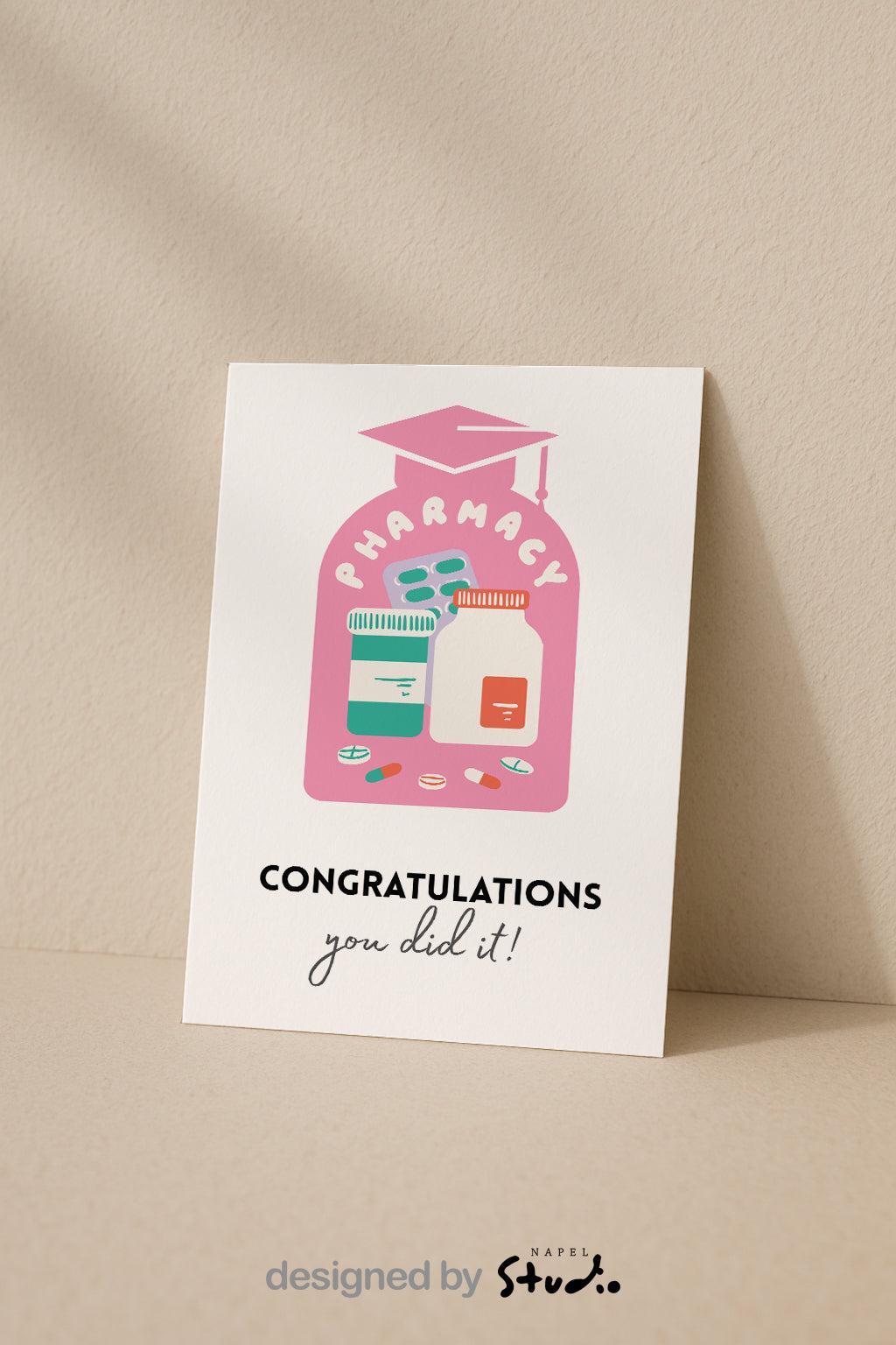 Illustration einer rosa Apotheker-Graduationkarte mit Abschlusskappe. In der Mitte stehen Medikamentenflaschen, Blistertabletten und bunte Pillen. Darüber der Schriftzug „Pharmacy“ in verspielten weißen Buchstaben. Unten steht „Congratulations – you did it!“. Perfekt als Glückwunschkarte für Pharma-Abschluss, Examen oder Apothekenberufe.