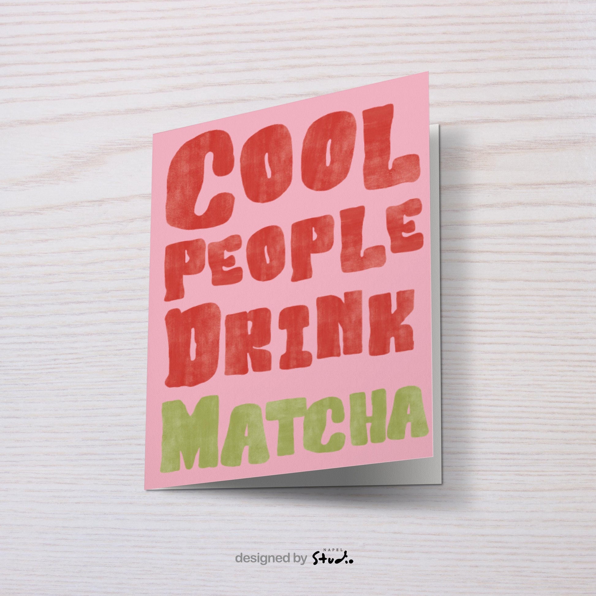 Lustige A6 Grußkarte mit modernem Typografie-Design auf rosa Hintergrund. In großen, leicht strukturierten Buchstaben steht „Cool People Drink Matcha“. Die Schrift ist rot und grün gehalten, im handgemalten Look. Perfekt als witzige Karte für Matcha-Fans, Freunde oder als Geschenkidee.