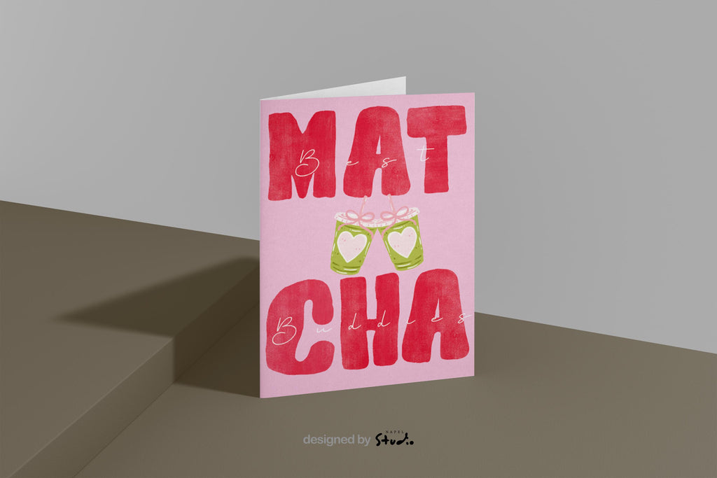 A6 Grußkarte mit rosa Hintergrund und großem roten Typografie-Text „MATCHA“. Dazwischen steht in feiner Handschrift „Best Buddies“. In der Mitte zwei gezeichnete Matcha-Becher mit Herzen, die anstoßen. Süßes, modernes Design ideal für Freundschaft, Geschenke und Matcha-Fans.