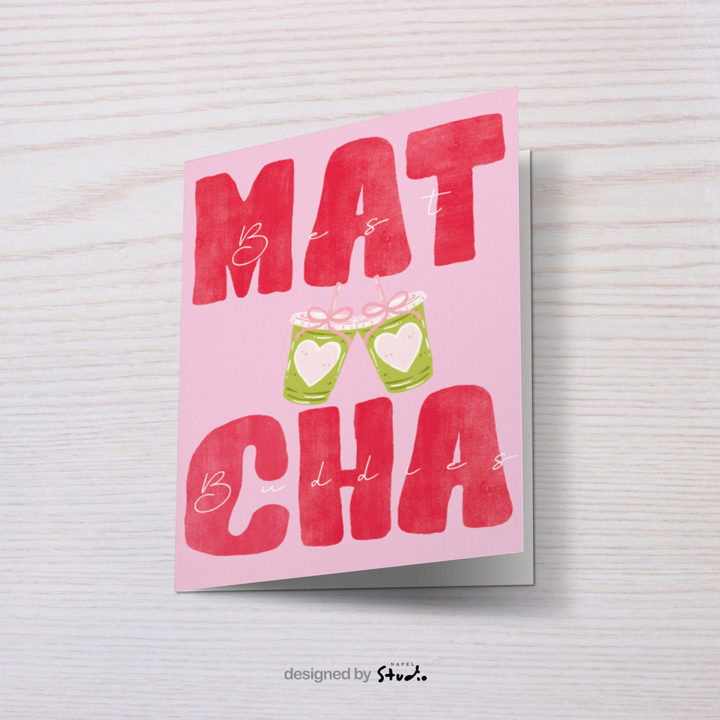 A6 Grußkarte mit rosa Hintergrund und großem roten Typografie-Text „MATCHA“. Dazwischen steht in feiner Handschrift „Best Buddies“. In der Mitte zwei gezeichnete Matcha-Becher mit Herzen, die anstoßen. Süßes, modernes Design ideal für Freundschaft, Geschenke und Matcha-Fans.
