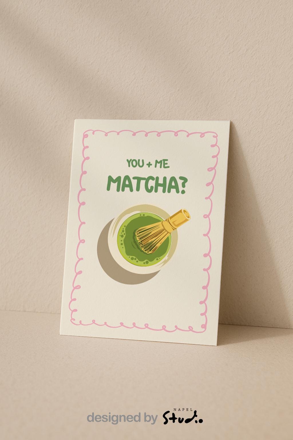 A6 Grußkarte mit heller cremefarbener Fläche und rosa Rahmen. Oben steht der Text „You + Me Matcha?“ in grüner Schrift. Darunter eine Illustration einer Matcha-Schale mit Bambusbesen. Süßes, verspieltes Design für Partner, Freundschaft oder Matcha-Fans.