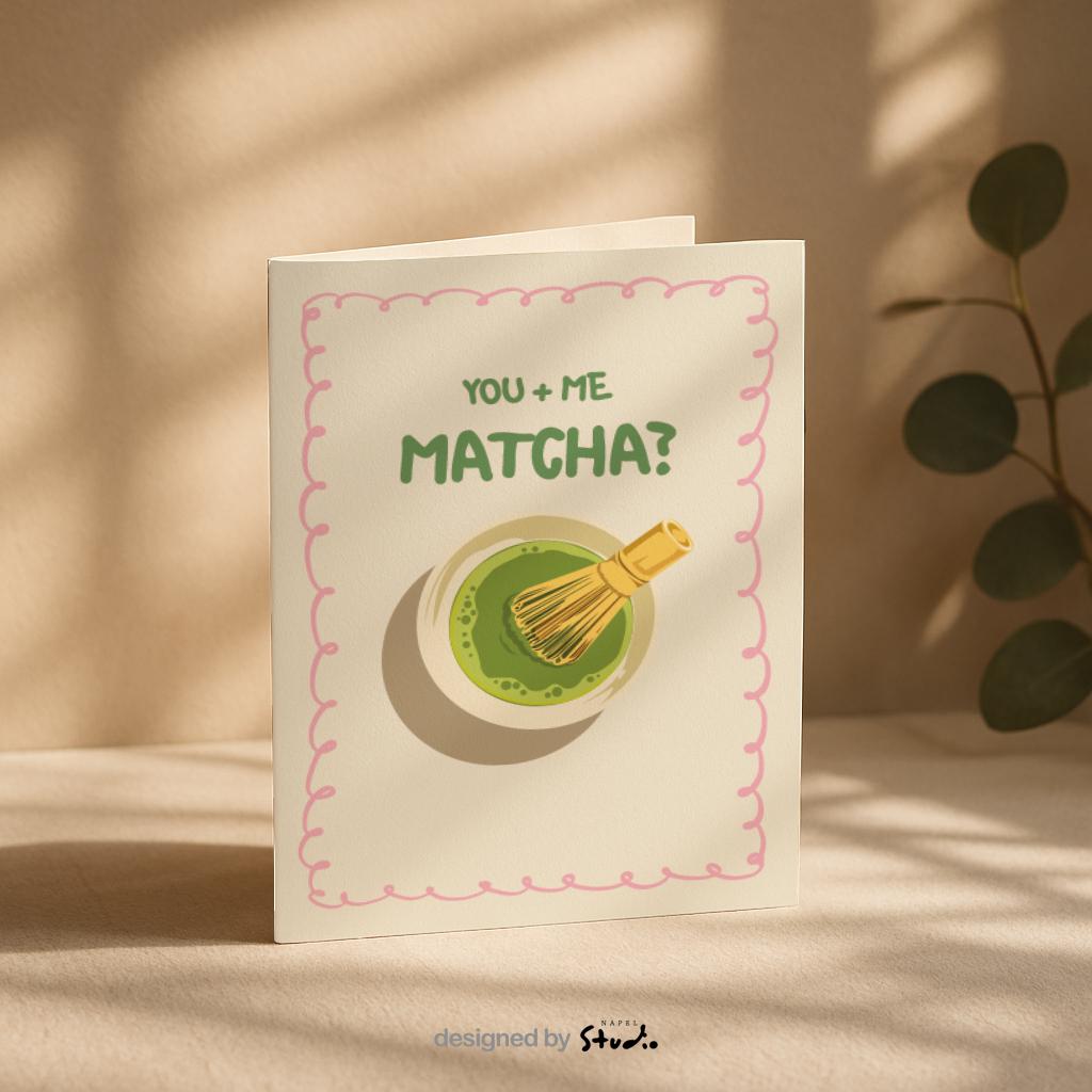 A6 Grußkarte mit heller cremefarbener Fläche und rosa Rahmen. Oben steht der Text „You + Me Matcha?“ in grüner Schrift. Darunter eine Illustration einer Matcha-Schale mit Bambusbesen. Süßes, verspieltes Design für Partner, Freundschaft oder Matcha-Fans.