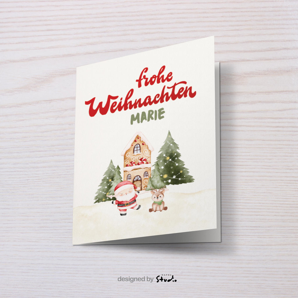A6 Weihnachtskarte mit hellbeigem Hintergrund und roter Schrift „Frohe Weihnachten“. Darunter der personalisierte Name „Marie“. Unten steht ein gezeichneter Weihnachtsmann neben einem kleinen Reh vor einem Lebkuchenhaus und zwei geschmückten Tannenbäumen. Süße, warme Illustration für Kinder, Familie und personalisierte Weihnachtsgrüße.