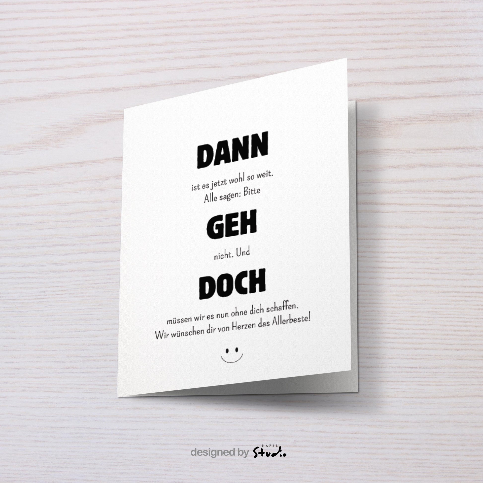 Weiße Abschiedskarte mit dem Spruch „Dann geh doch“ in großer, schwarzer Typografie. Dazwischen kleinerer Text im minimalistischen Stil. Humorvolle, moderne Gestaltung mit kleinem Smiley unten. Karte liegt auf einem hellbraunen Umschlag. Ideal für Kollegen, die das Team verlassen oder den Job wechseln.