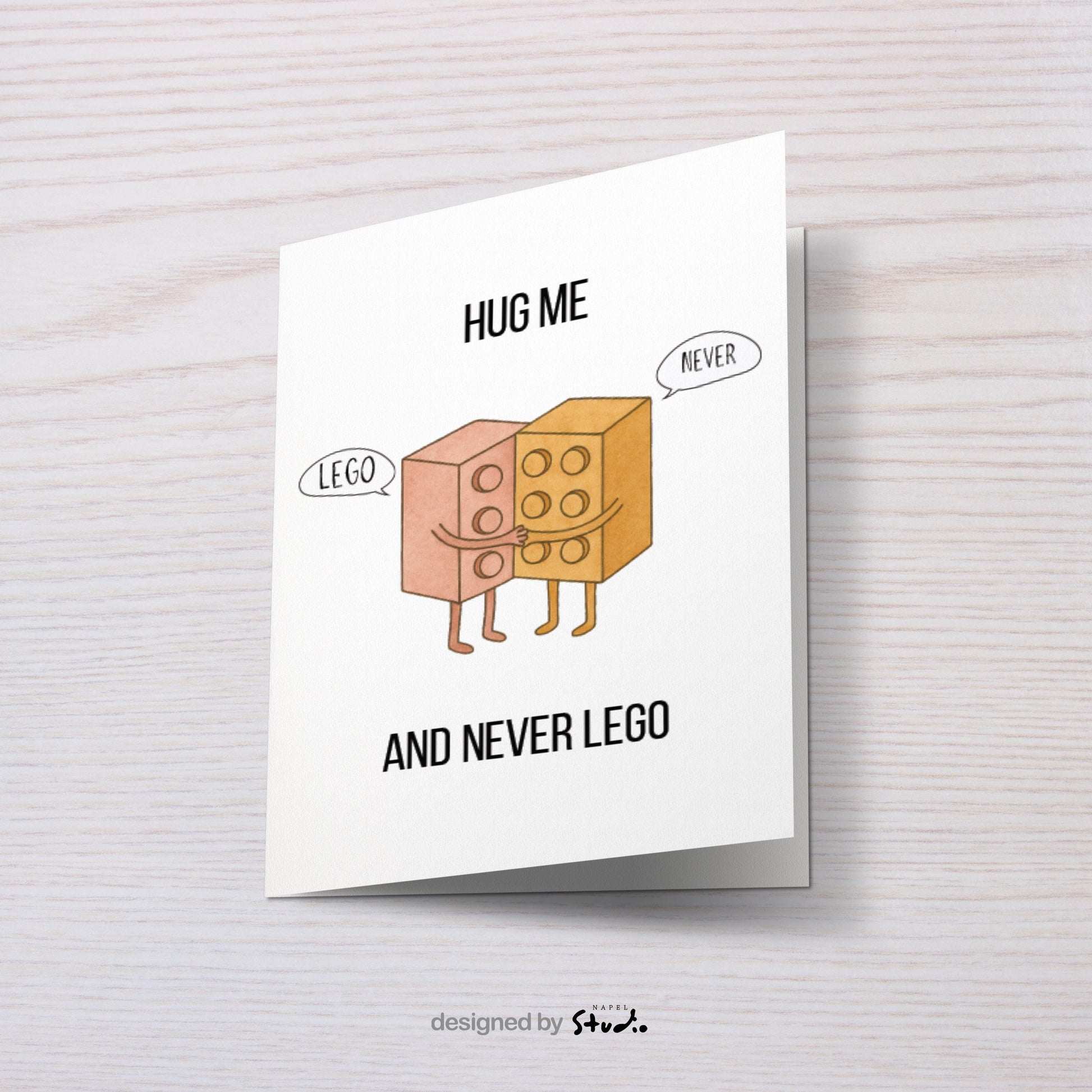 Witzige A6-Grußkarte mit zwei umarmenden Bausteinen im Cartoon-Stil. Der Text „Hug me and never LEGO“ spielt humorvoll auf ein Wortspiel an. Die Figuren wirken süß und freundlich, mit Sprechblasen „Lego“ und „Never“. Minimalistisches, helles Design, ideal als liebevolle und humorvolle Karte für Partner oder Freunde.