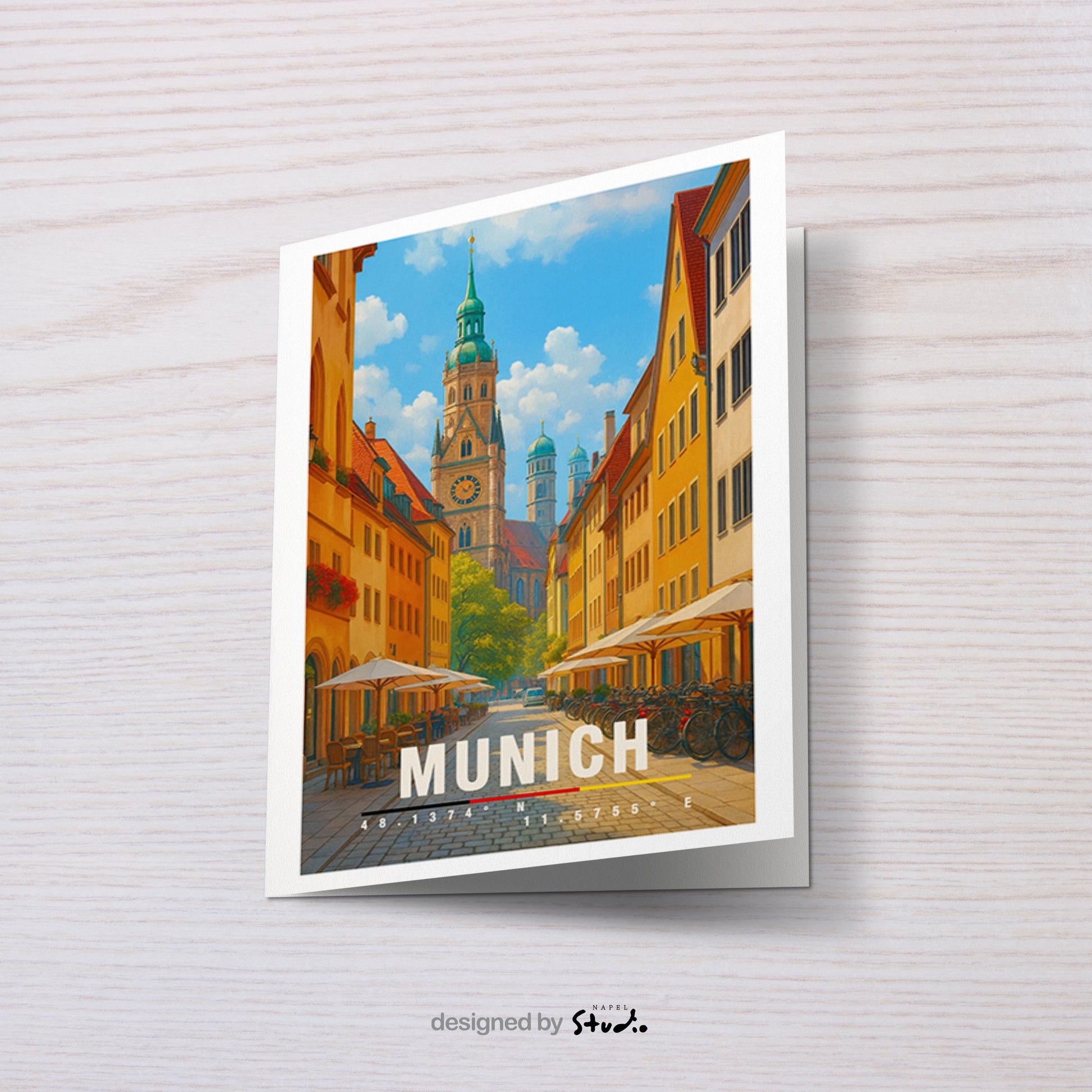 A6-Grußkarte mit München-Illustration: Blick durch eine gemütliche Altstadtstraße mit Cafés und Fahrrädern auf historische Türme und Dächer. Warme Farben, klare Linien und moderner Travel-Poster-Stil. Ideal als Reise- oder Souvenirkarte für München- und Bayern-Liebhaber.