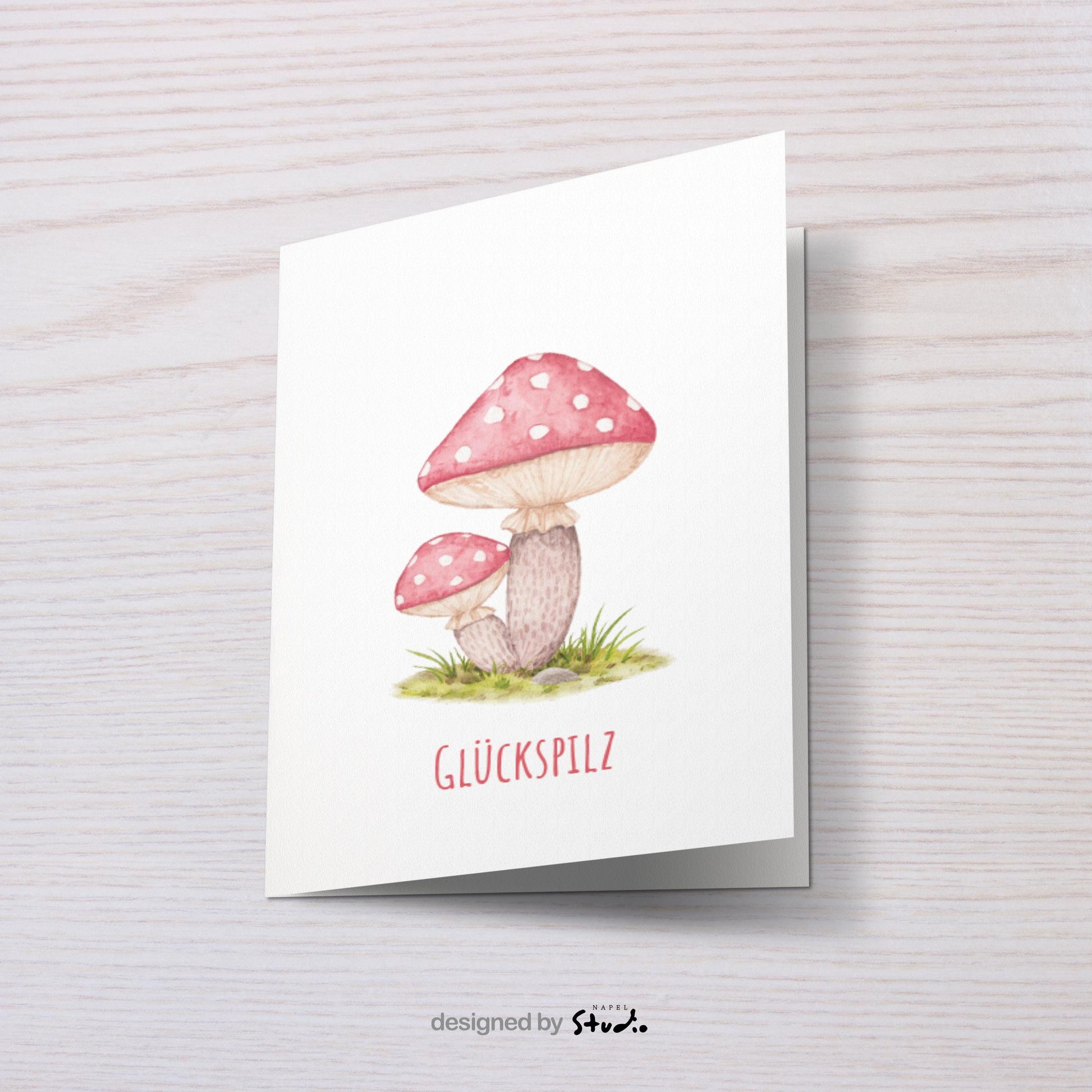 Aquarell-Illustration von zwei roten Fliegenpilzen mit weißen Punkten auf einer grünen Wiese. Darunter steht der Schriftzug „Glückspilz“. Die Karte vermittelt Glück, Wärme und Naturverbundenheit und eignet sich perfekt als Geburtstagskarte, Glückwunschkarte oder kleine Aufmerksamkeit für liebe Menschen.