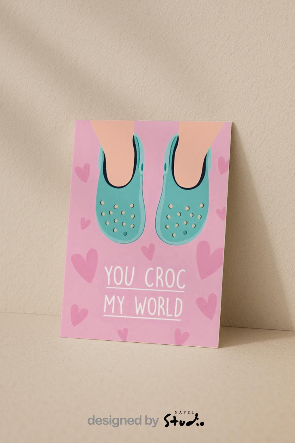 Verspielte Illustration von türkisfarbenen Crocs vor rosafarbenem Hintergrund mit kleinen Herzmotiven. Der Text „You croc my world“ nutzt ein humorvolles Wortspiel und macht die Karte liebevoll und witzig zugleich. Ideal als Valentinstagskarte, Jahrestagskarte oder als lustige Liebeskarte für Partner, Freunde oder Crocs-Fans.