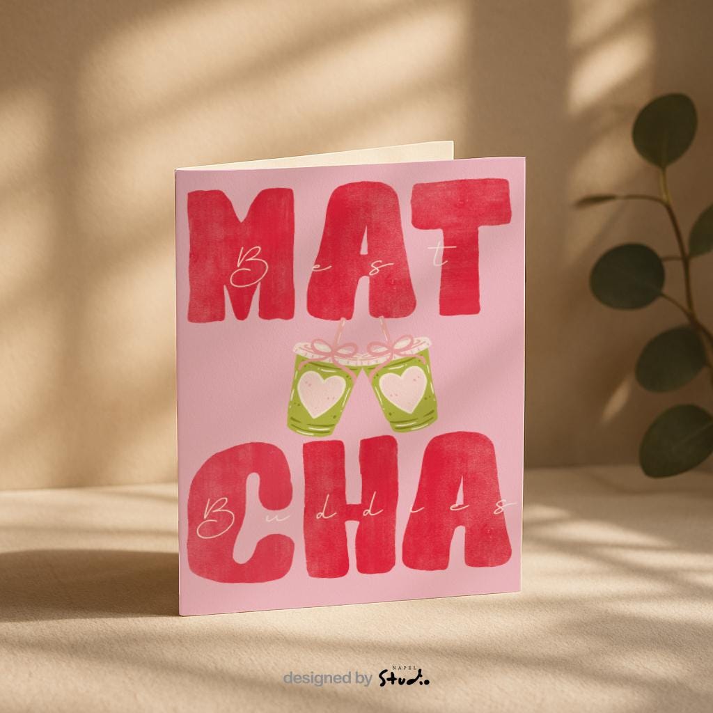 A6 Grußkarte mit rosa Hintergrund und großem roten Typografie-Text „MATCHA“. Dazwischen steht in feiner Handschrift „Best Buddies“. In der Mitte zwei gezeichnete Matcha-Becher mit Herzen, die anstoßen. Süßes, modernes Design ideal für Freundschaft, Geschenke und Matcha-Fans.