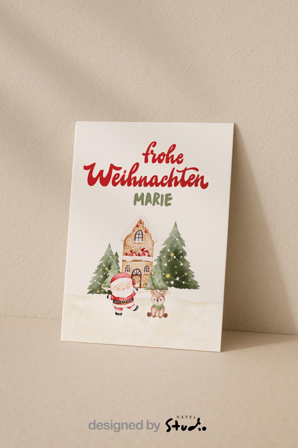 A6 Weihnachtskarte mit hellbeigem Hintergrund und roter Schrift „Frohe Weihnachten“. Darunter der personalisierte Name „Marie“. Unten steht ein gezeichneter Weihnachtsmann neben einem kleinen Reh vor einem Lebkuchenhaus und zwei geschmückten Tannenbäumen. Süße, warme Illustration für Kinder, Familie und personalisierte Weihnachtsgrüße.