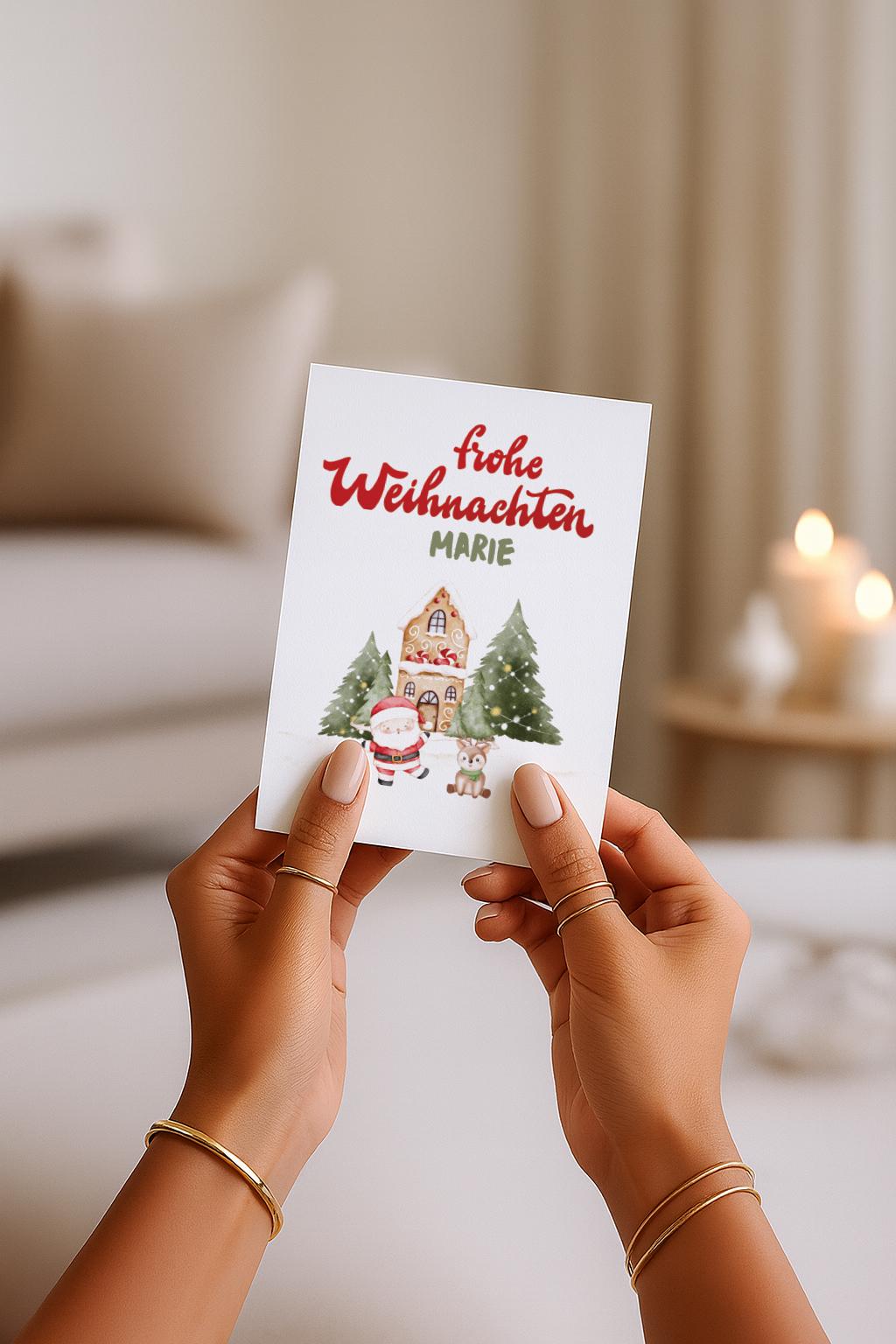 A6 Weihnachtskarte mit hellbeigem Hintergrund und roter Schrift „Frohe Weihnachten“. Darunter der personalisierte Name „Marie“. Unten steht ein gezeichneter Weihnachtsmann neben einem kleinen Reh vor einem Lebkuchenhaus und zwei geschmückten Tannenbäumen. Süße, warme Illustration für Kinder, Familie und personalisierte Weihnachtsgrüße.