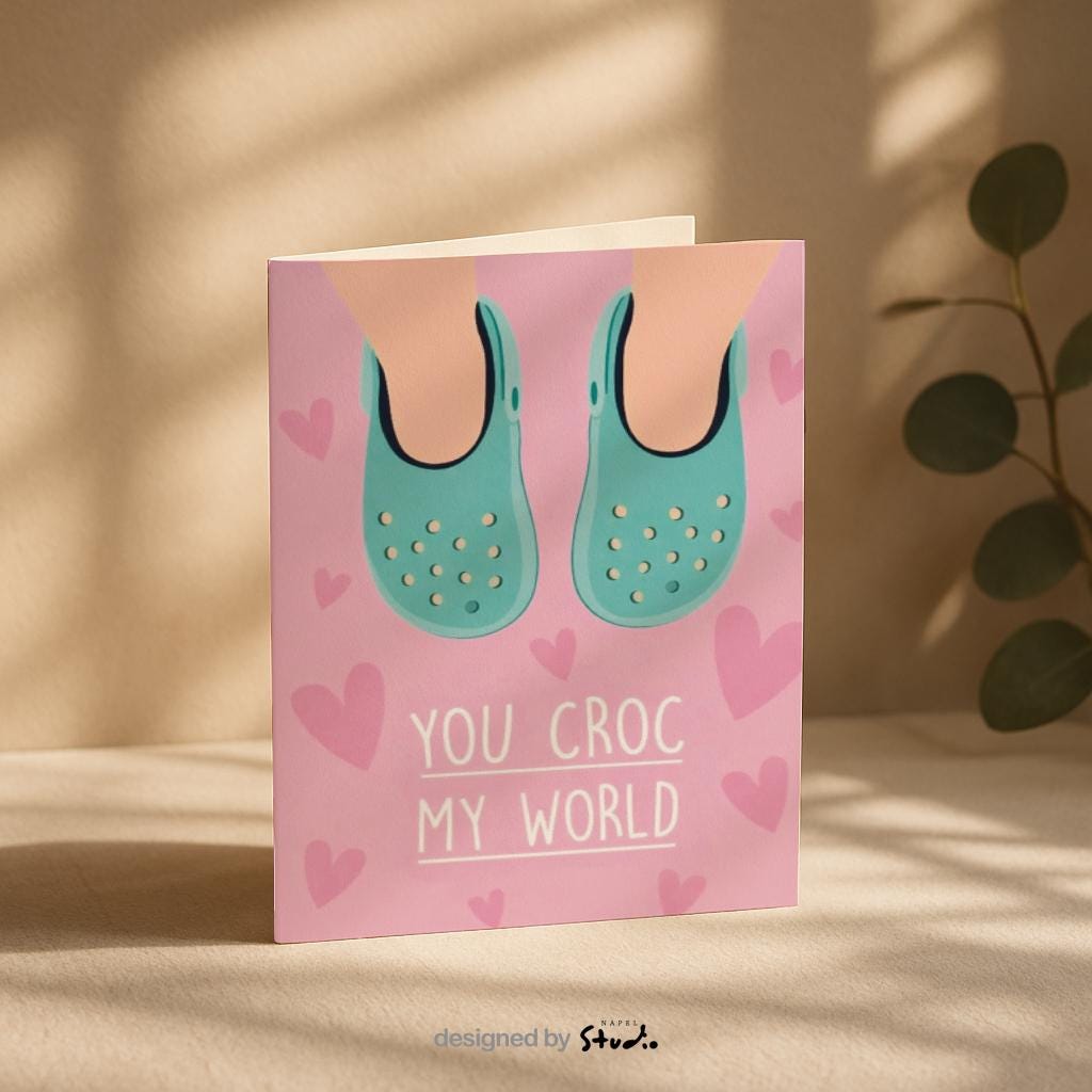 Verspielte Illustration von türkisfarbenen Crocs vor rosafarbenem Hintergrund mit kleinen Herzmotiven. Der Text „You croc my world“ nutzt ein humorvolles Wortspiel und macht die Karte liebevoll und witzig zugleich. Ideal als Valentinstagskarte, Jahrestagskarte oder als lustige Liebeskarte für Partner, Freunde oder Crocs-Fans.