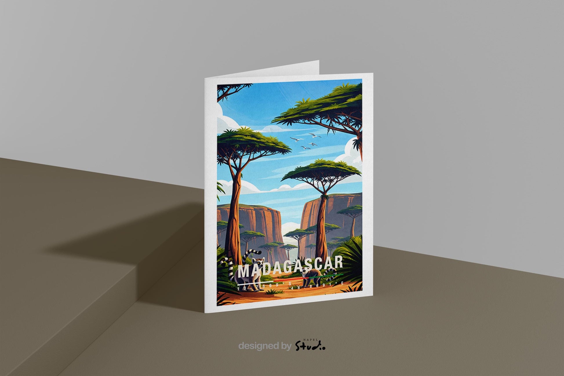 Illustrative Grußkarte mit einer warmen, farbenfrohen Landschaft aus Madagaskar. Im Vordergrund stehen zwei Lemuren auf einem sandfarbenen Pfad, umgeben von üppigem Grün und typischen Pflanzen. Hohe, charakteristische Bäume mit flachen Kronen prägen die Szenerie, während sich im Hintergrund felsige Schluchten und eine weite Naturkulisse unter blauem Himmel mit sanften Wolken erstrecken. Fliegende Vögel verleihen dem Motiv Leichtigkeit und Tiefe. Die Karte vermittelt Abenteuer, Exotik.