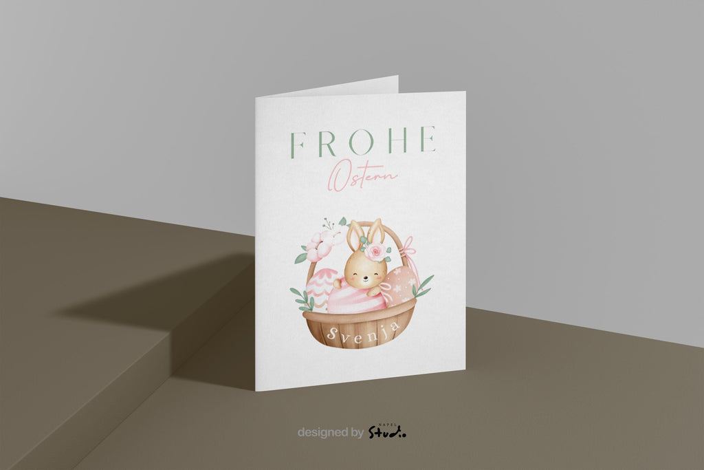 Personalisierte Oster Grußkarte mit niedlichem Hasen im Körbchen und dekorativen Ostereiern, sanfte Pastellfarben und verspieltes Design, ideal für Kinder, Familie oder als liebevolle Osterüberraschung, fröhliche Osterkarte mit Platz für individuellen Namen.