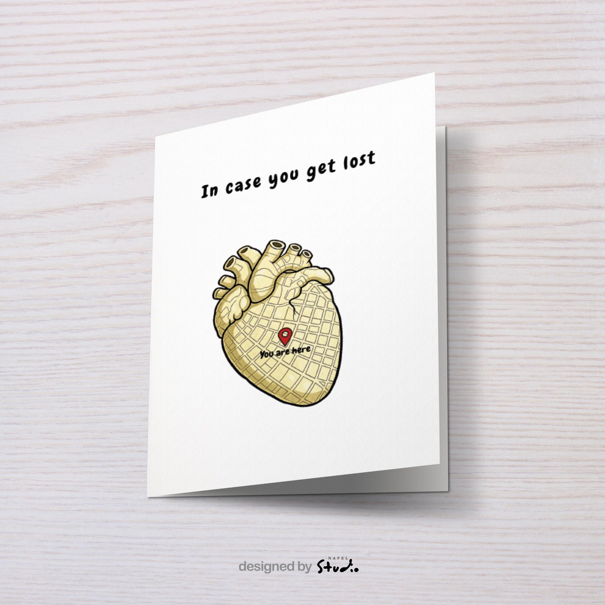 Illustration eines anatomischen Herzens, das wie eine Stadtkarte gestaltet ist. In der Mitte befindet sich ein roter Standort-Pin mit dem Text „You are here“. Darüber steht der Schriftzug „In case you get lost“. Die Karte verbindet Humor, Anatomie und Liebe und eignet sich perfekt als besondere Grußkarte für Partner, Freunde oder als kleine Aufmerksamkeit.