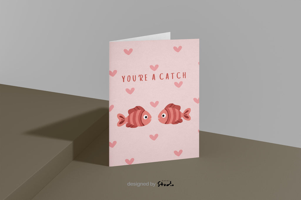 Illustration von zwei Fischen, die sich gegenüberstehen, umgeben von kleinen Herzen. Der Text „You’re a catch“ macht die Karte zu einer charmanten Liebeskarte mit Wortspiel. Ideal für Valentinstag, Jahrestag oder als kleine romantische Aufmerksamkeit.