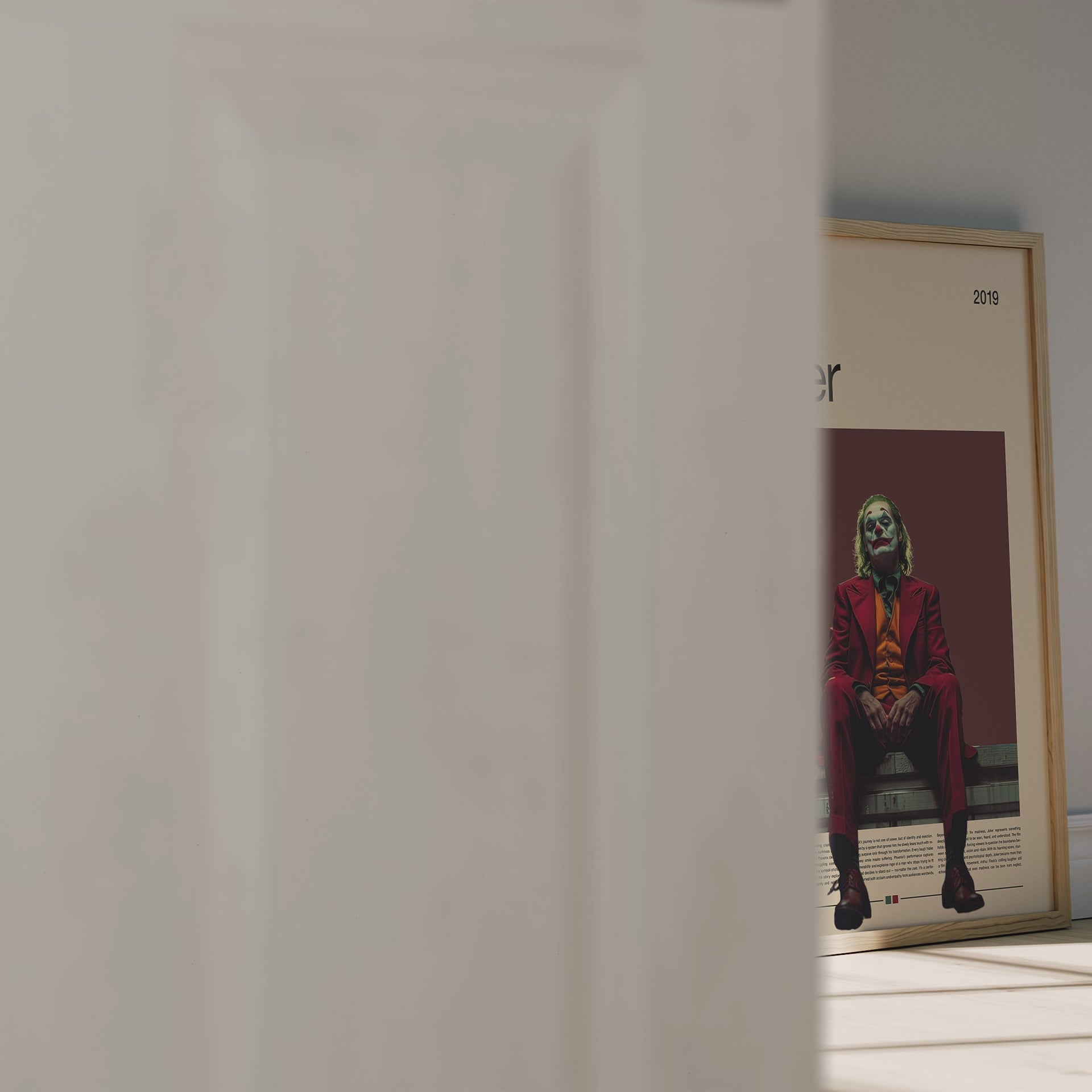 Minimalist Joker poster featuring Joaquin Phoenix in a red suit sitting under moody lighting on a dark red background. Inspired by the 2019 film Joker, this cinematic artwork captures emotion, isolation, and power – ideal for film enthusiasts and modern wall decor lovers.